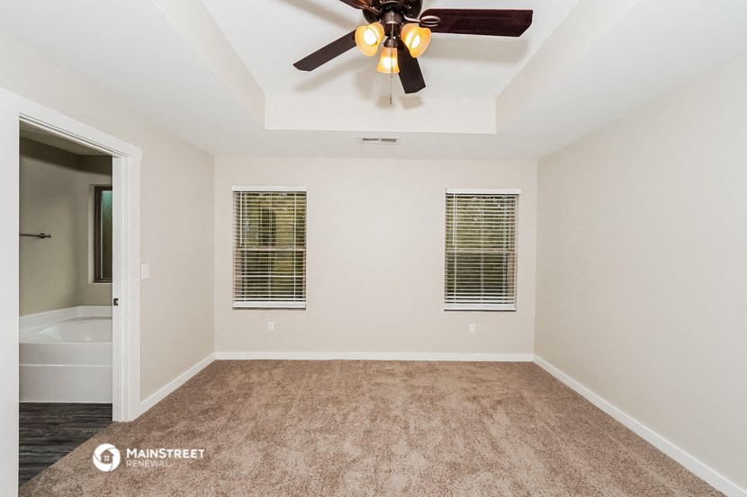 a empty bedroom with a ceiling fan and a bathroom
