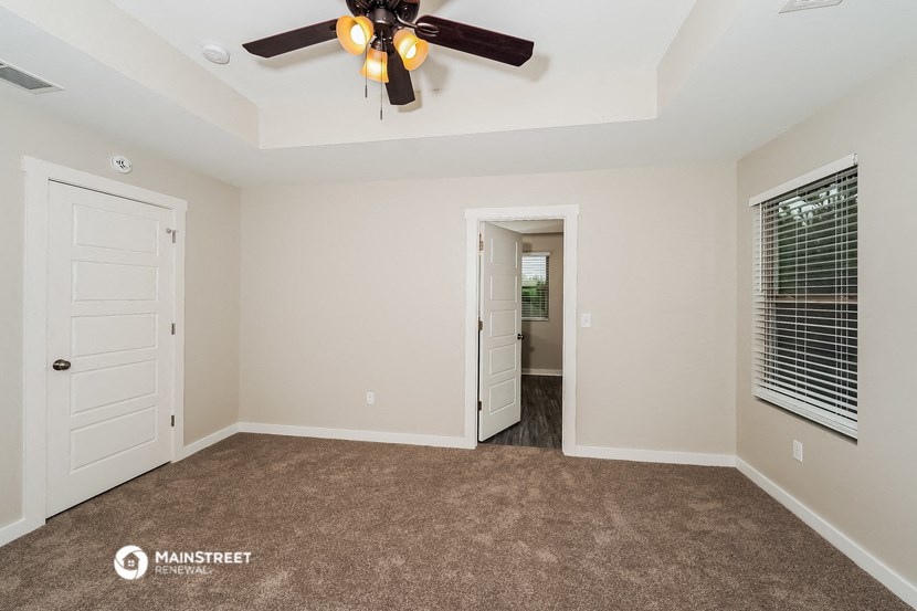 a living room with a ceiling fan and a door to a hallway