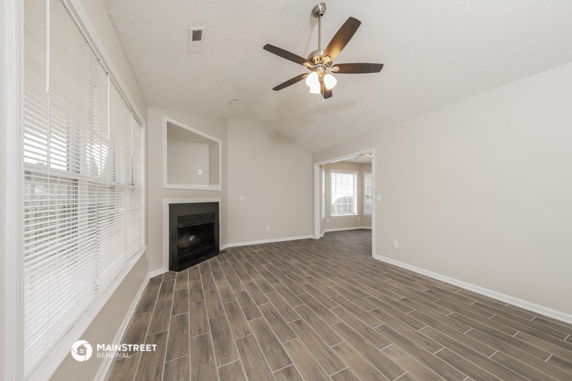the living room has a fireplace and a ceiling fan
