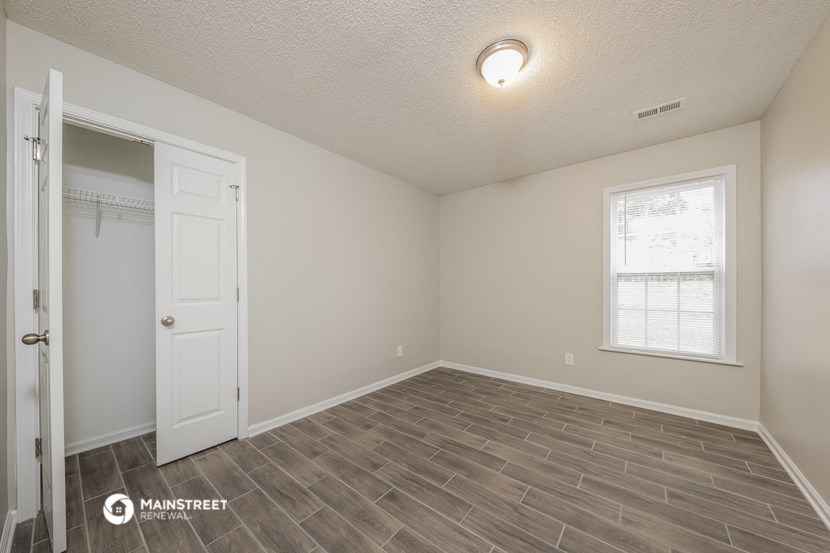 the spacious living room with wood flooring and a door to the closet