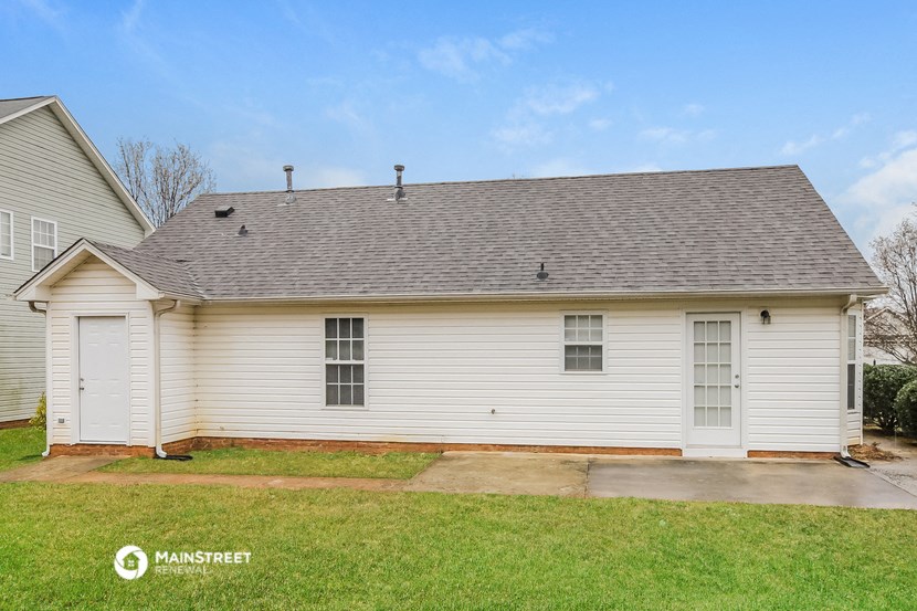 the front view of a white house with a gray roof and a driveway