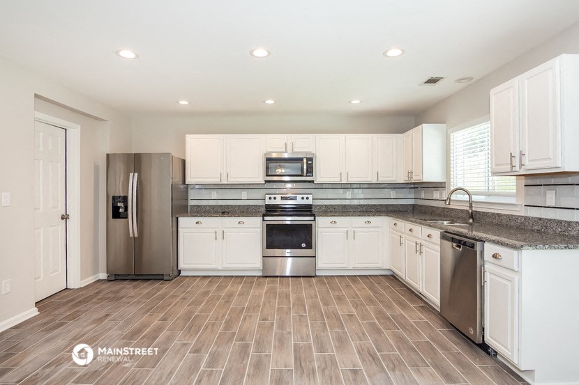 a large kitchen with white cabinets and stainless steel appliances