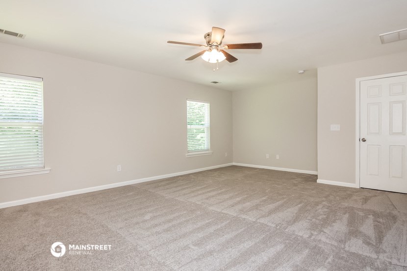 the spacious living room with ceiling fan and carpet