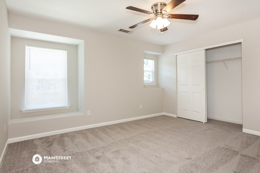 the spacious bedroom with closet and ceiling fan