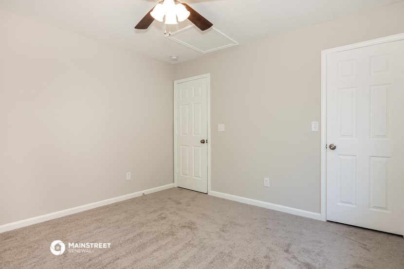 a bedroom with two doors and a ceiling fan