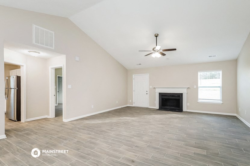 the living room with a fireplace and a ceiling fan