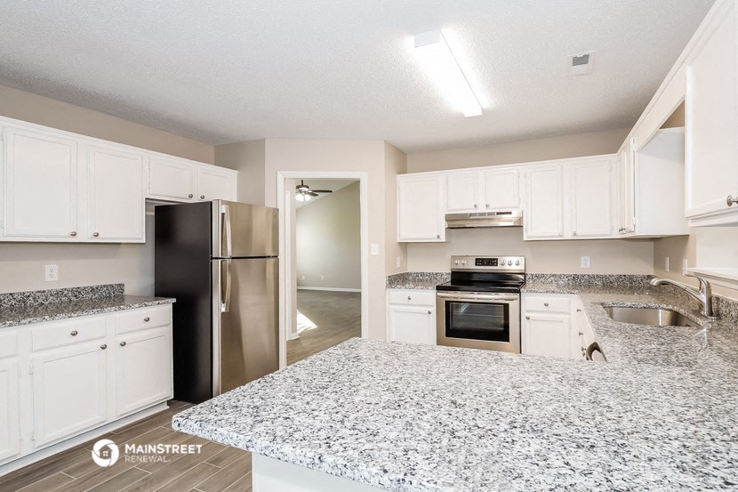 a kitchen with white cabinets and granite counter tops and stainless steel appliances