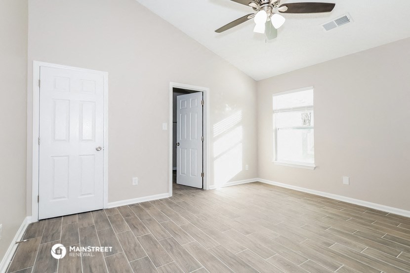 the living room of an empty home with a ceiling fan
