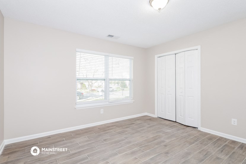 the spacious living room with white walls and wood flooring