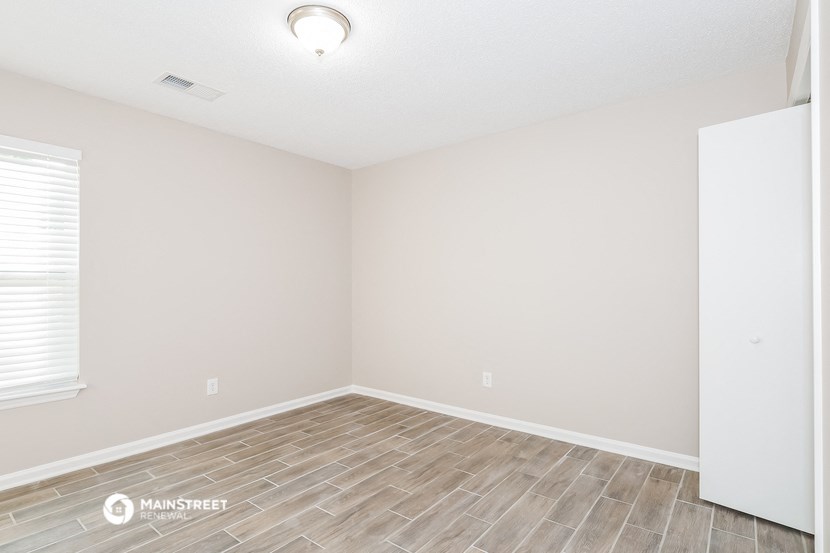 the spacious living room with wood flooring and white walls