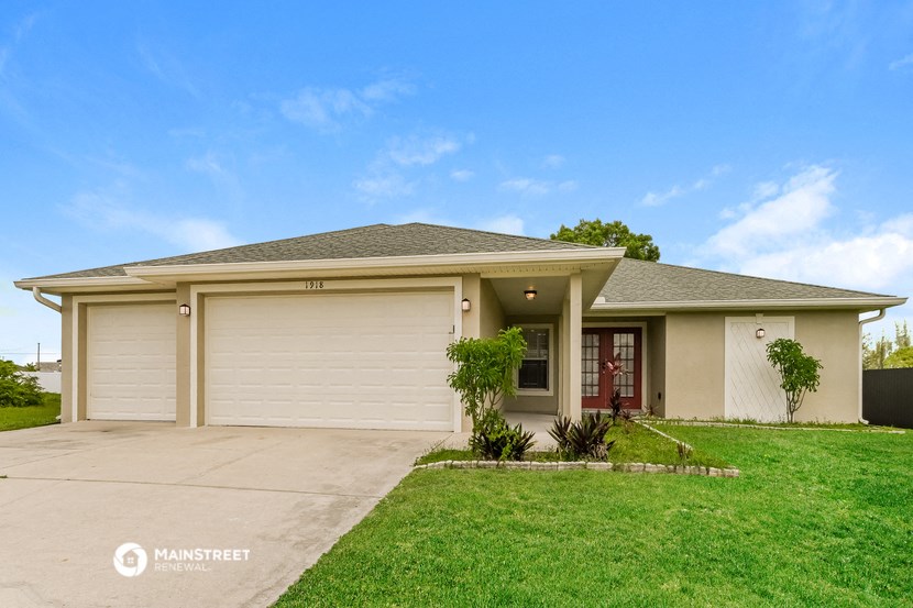 a beige house with a garage door and a lawn