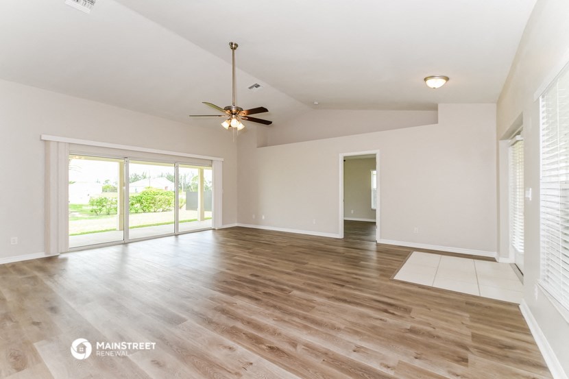 an empty living room with wood flooring and a ceiling fan
