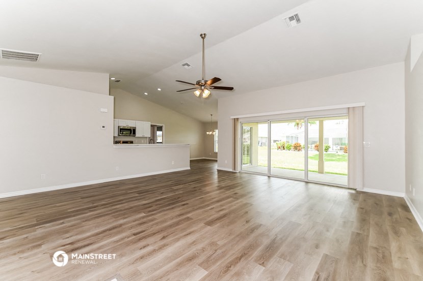 the living room and dining room of a house with wood floors and a ceiling fan