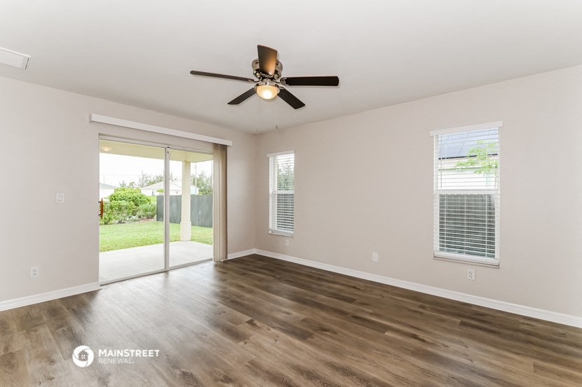 an empty living room with a ceiling fan and a sliding glass door