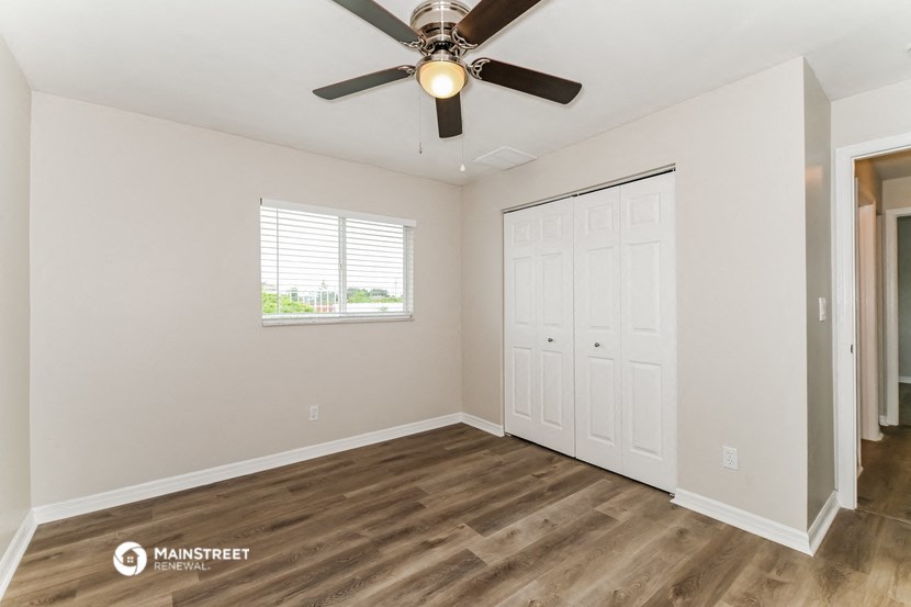 the spacious living room with a ceiling fan and a closet