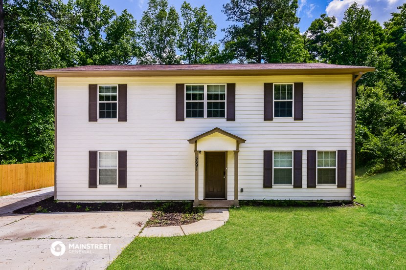 a small white house with black shutters and a yard and grass