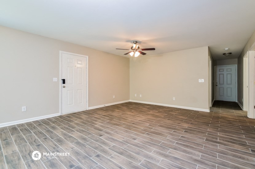 the spacious living room with wood flooring and ceiling fan