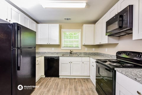 a kitchen with white cabinets and black appliances