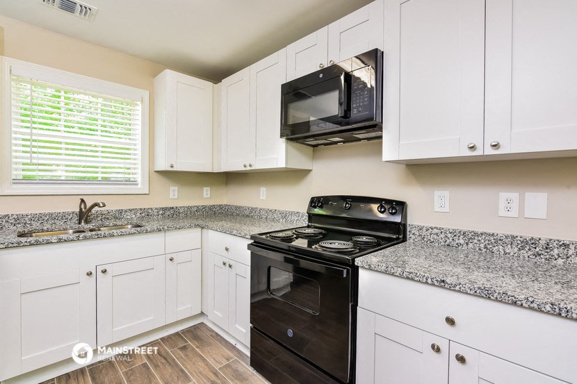 a kitchen with white cabinets and black appliances and granite counter tops