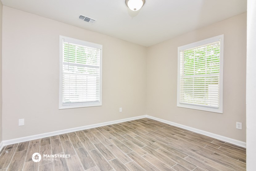 the spacious living room with wood flooring and two windows
