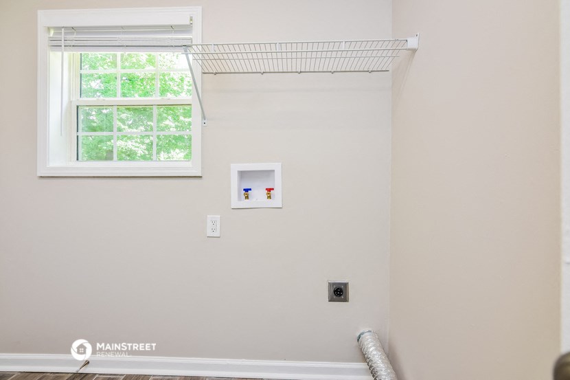 a white wall with a window and a white radiator and a wall mounted light fixture