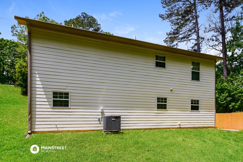 the side of a white house with a radiator in the grass