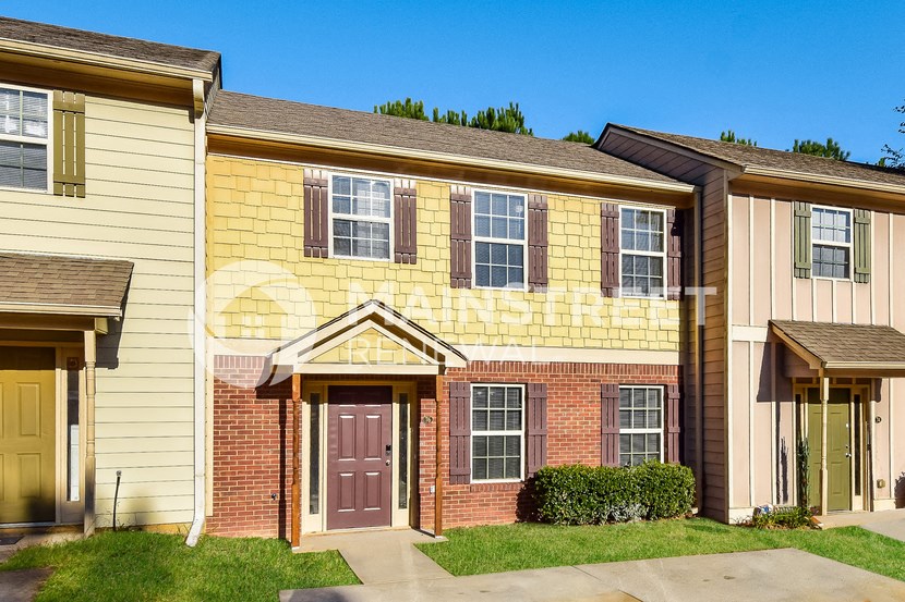 a yellow brick house with a purple door and a lawn