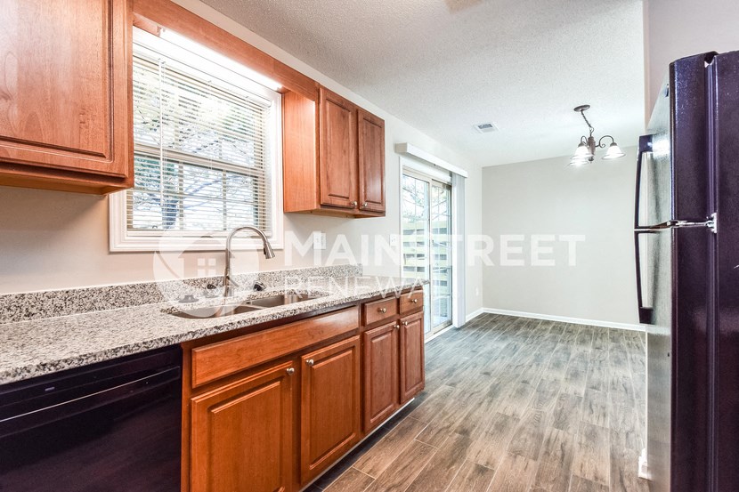a kitchen with wood cabinets and granite counter tops and a black refrigerator
