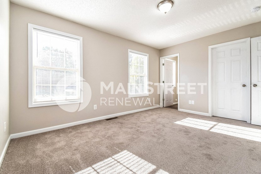 an empty living room with a white door and a closet
