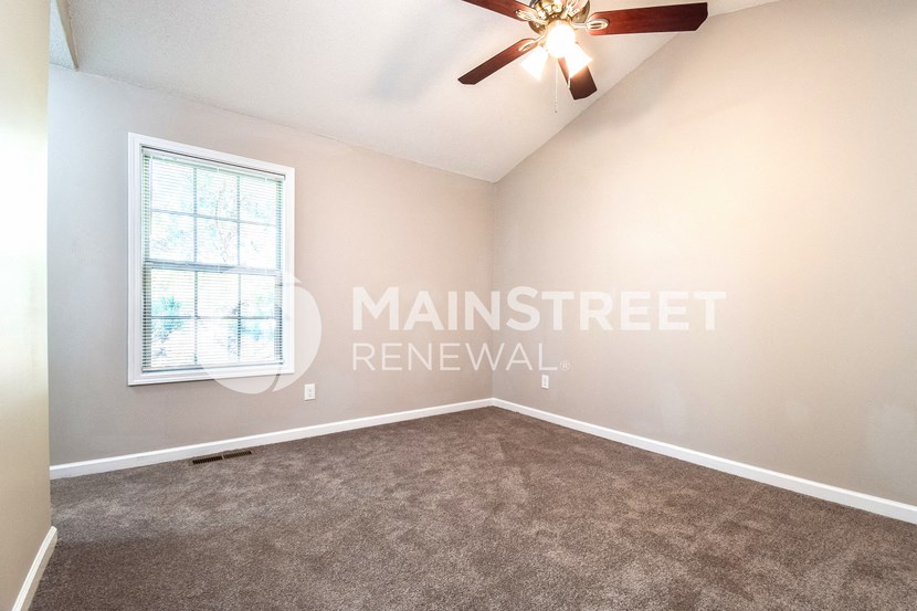an empty living room with carpet and a ceiling fan