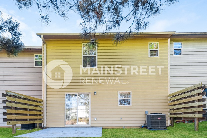 a yellow house with a garage and a yard with wooden fences