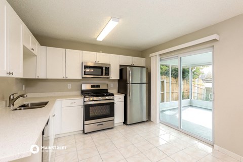 a kitchen with white cabinets and stainless steel appliances and a sliding glass door