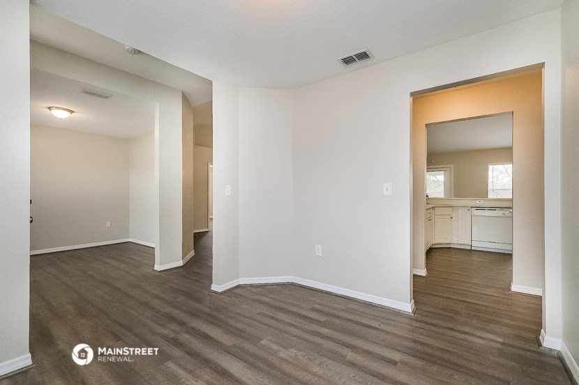 a spacious living room with white walls and wood flooring