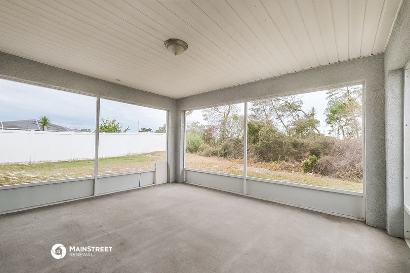 a screened in porch with large windows and a concrete floor