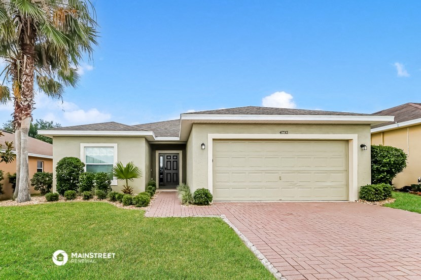 a yellow house with a garage door and a lawn