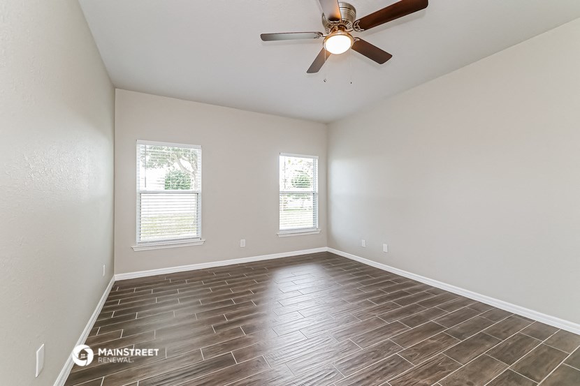 the living room of an empty house with a ceiling fan
