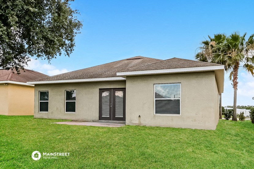 a beige house with palm trees and a lawn