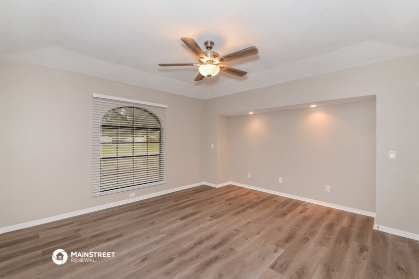 the spacious living room with hardwood floors and a ceiling fan