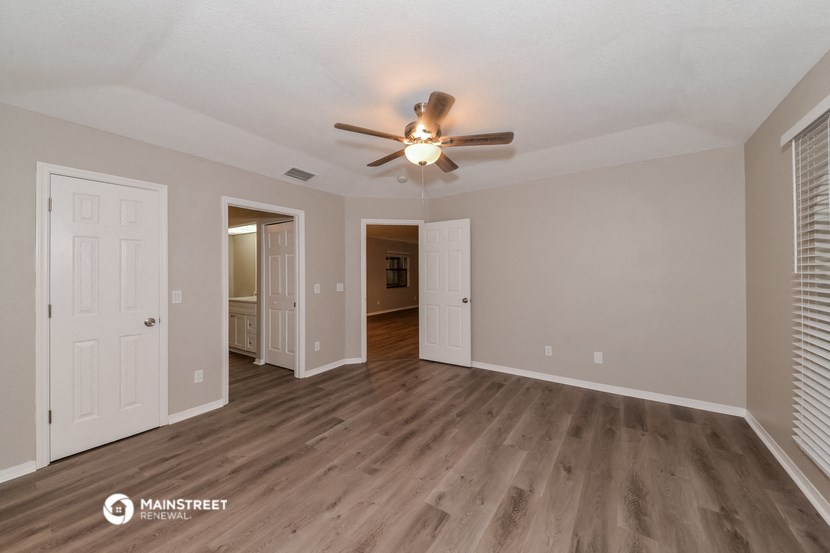 the spacious living room with ceiling fan and wood flooring