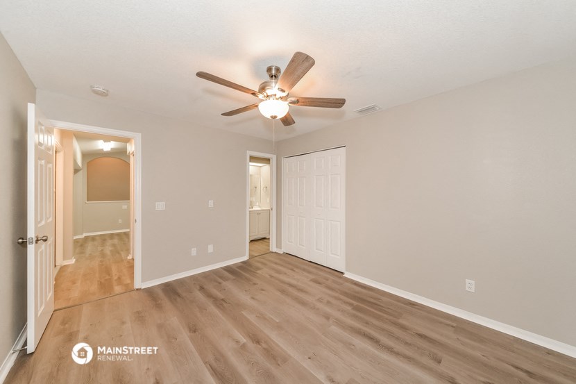 the spacious living room and dining room with hardwood flooring and a ceiling fan