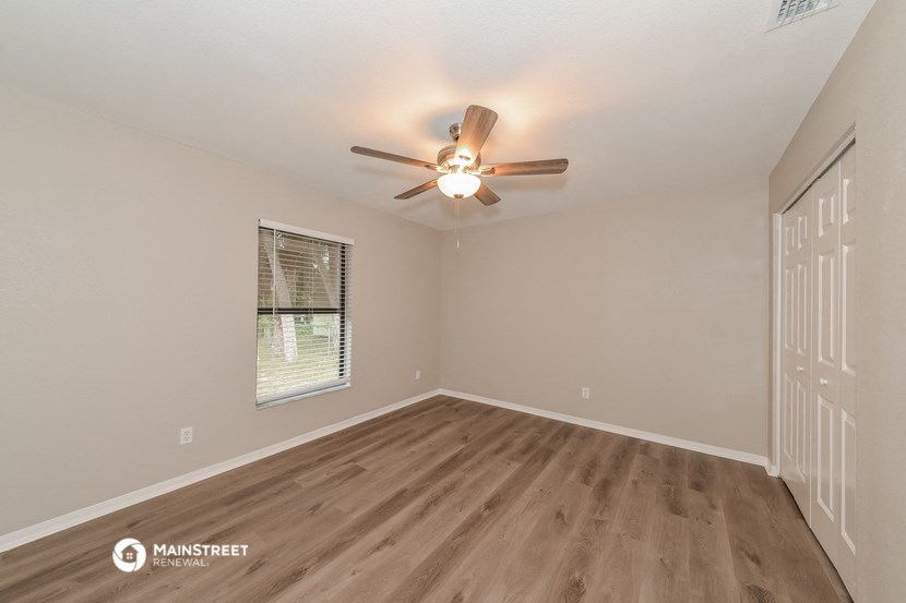 the spacious living room with ceiling fan and wood flooring
