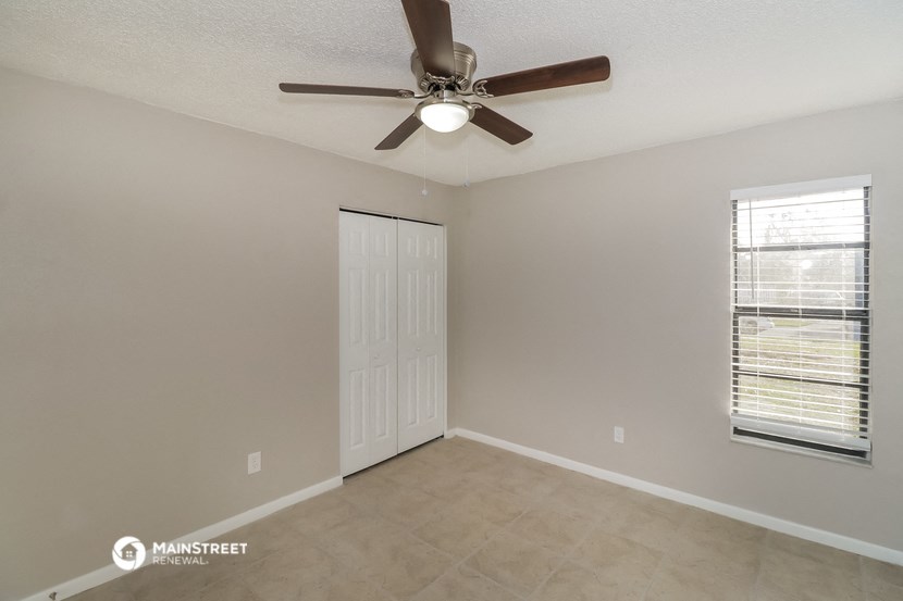 the spacious living room with ceiling fan and tile flooring