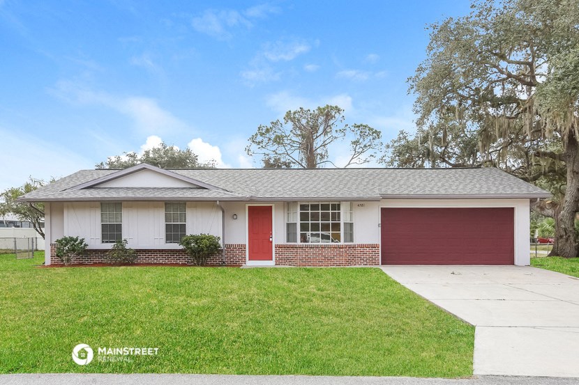 a white house with a red door and a lawn