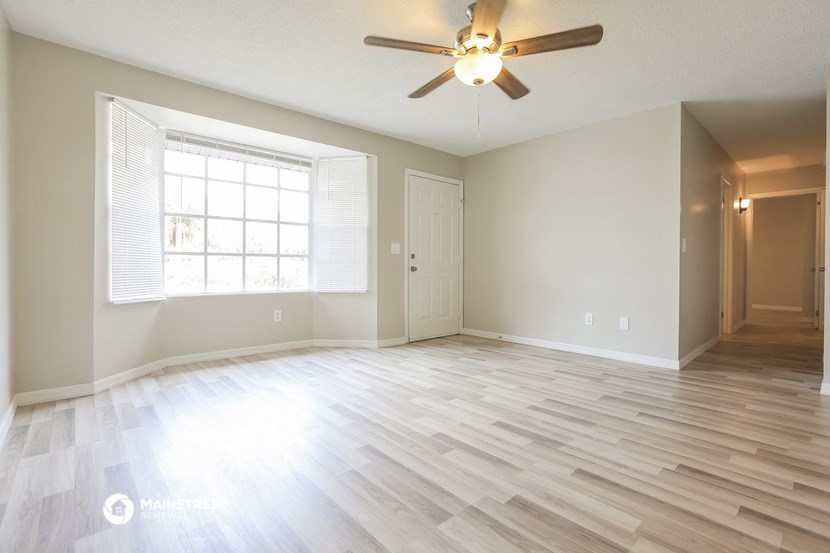 an empty living room with a ceiling fan and a window