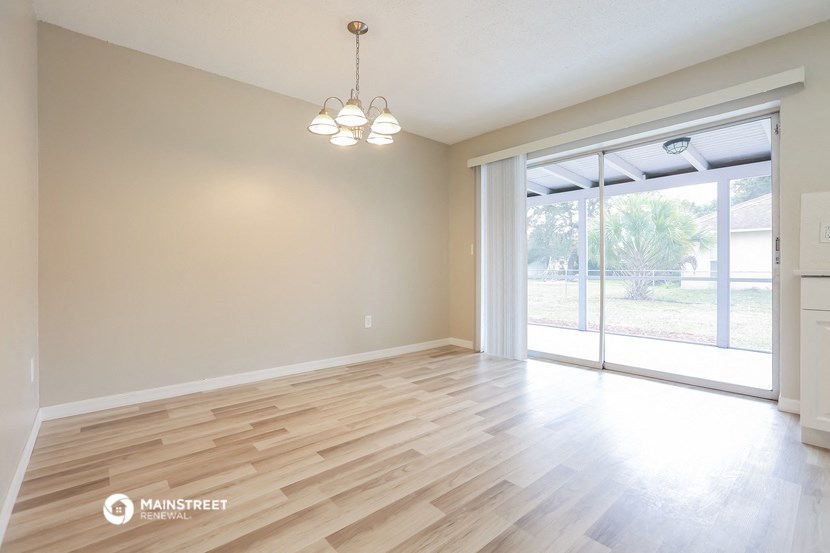 the living room and dining room of an empty house with wood flooring