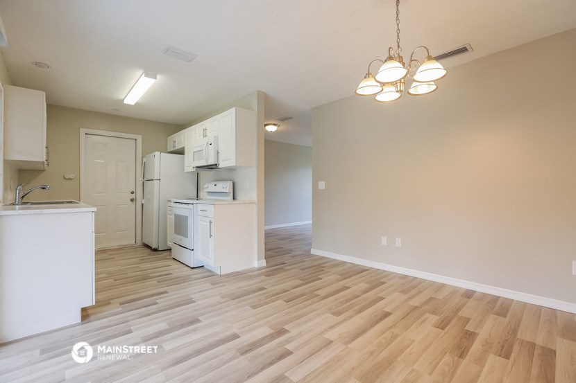 the living room and kitchen of an apartment with wood flooring