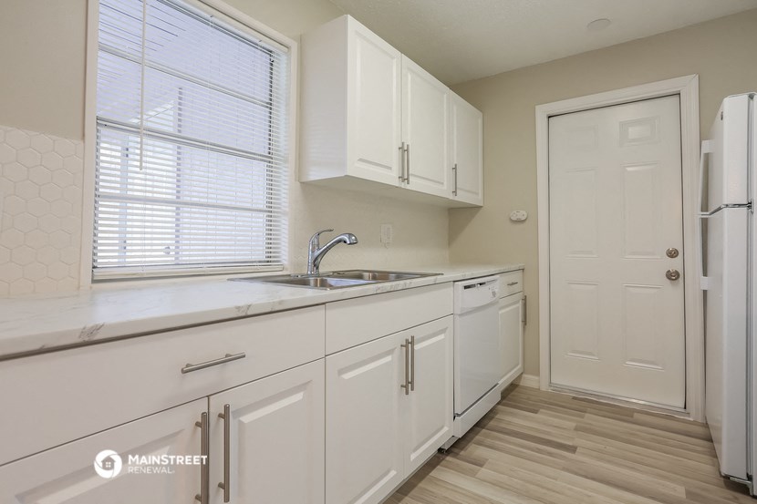 a kitchen with white cabinets and a sink and a refrigerator