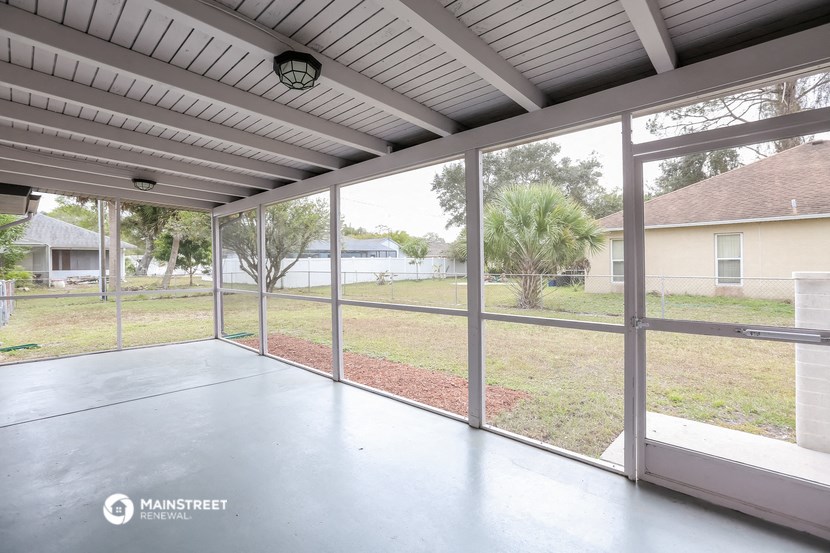 a screened in porch with glass doors and a view of the yard