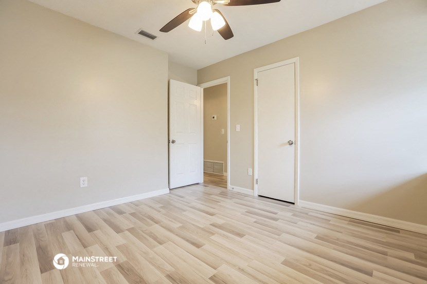 the living room of an empty house with wood flooring and a ceiling fan
