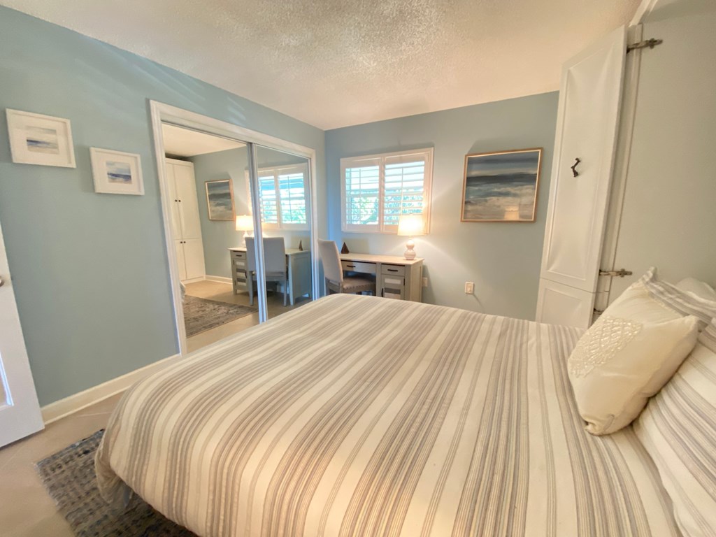 a bedroom with a large bed and a living room with a desk and a mirror